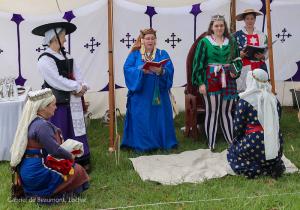 woman in medieval garb kneeling at a royal court